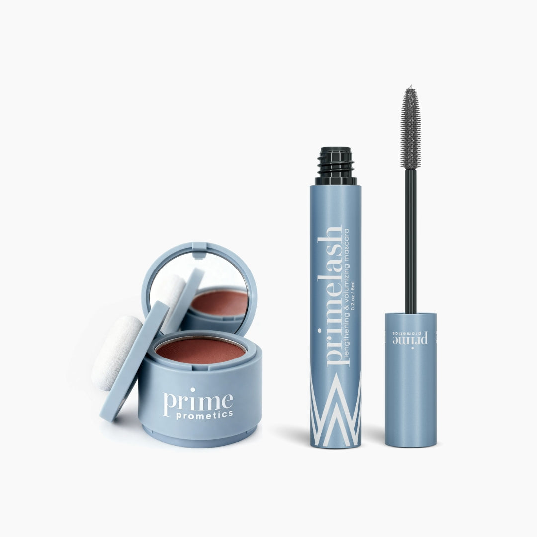 The PrimePrometics™ Beauty Essentials set, featuring a blue compact with blush and mirror beside an open PrimeLash mascara, is displayed on a plain white background.