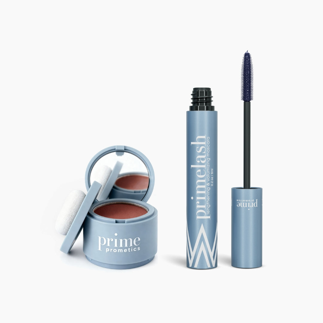 The Beauty Essentials set by PrimePrometics™ features a blue Hairline Powder compact with mirror and sponge beside a matching PrimeLash Mascara tube with exposed wand, all showcased on a white background.