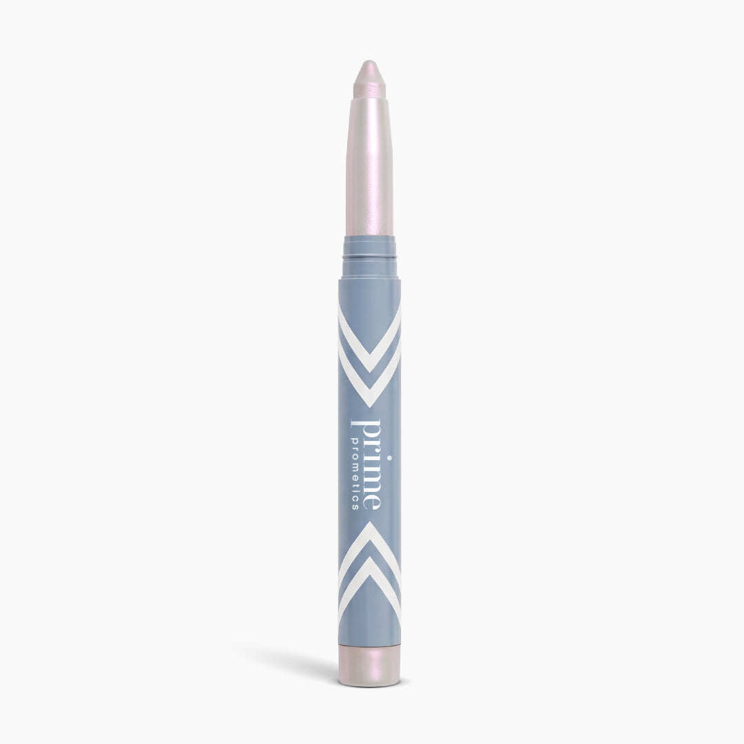 A silver and blue makeup stick with a twist-up creamy tip, labeled PrimePrometics™, stands upright on a white background—this illuminating eyeshadow, PrimeEyes Eye Brightener, is specially designed to create an instant eye lift effect, making it the ideal eyeshadow for women over 50.