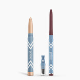 Two blue Eye Lift Duo makeup pencils by PrimePrometics™ stand upright—one with a beige tip, one with a dark brown tip—ideal eyeliner for women over 50. A small sharpener with a clear cap sits between them; all feature white chevrons and branding.