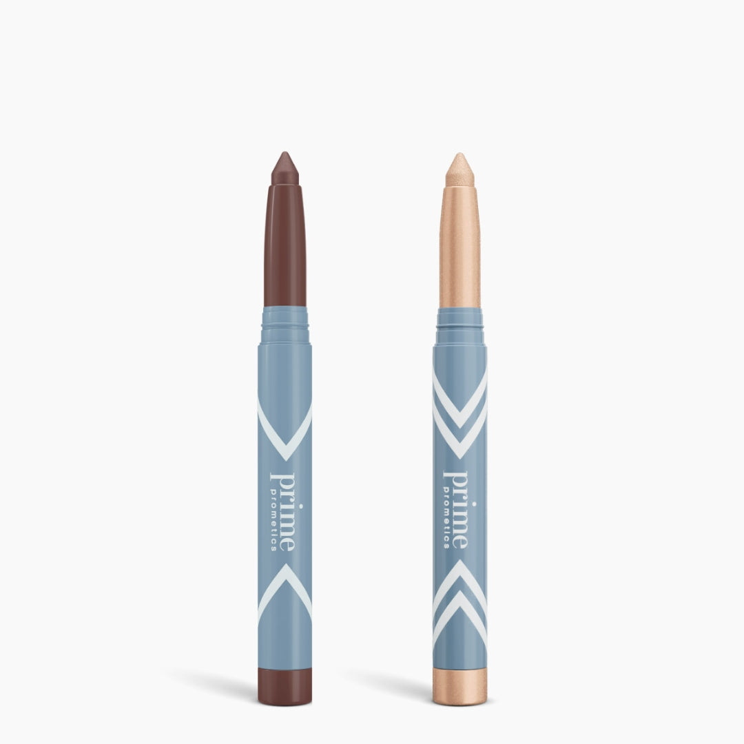 Two PrimePrometics™ Complete Eye Sticks Kit makeup sticks with blue packaging stand upright capless on white—left: deep brown Matte Eyeshadow, right: shimmery champagne Eye Brightener.