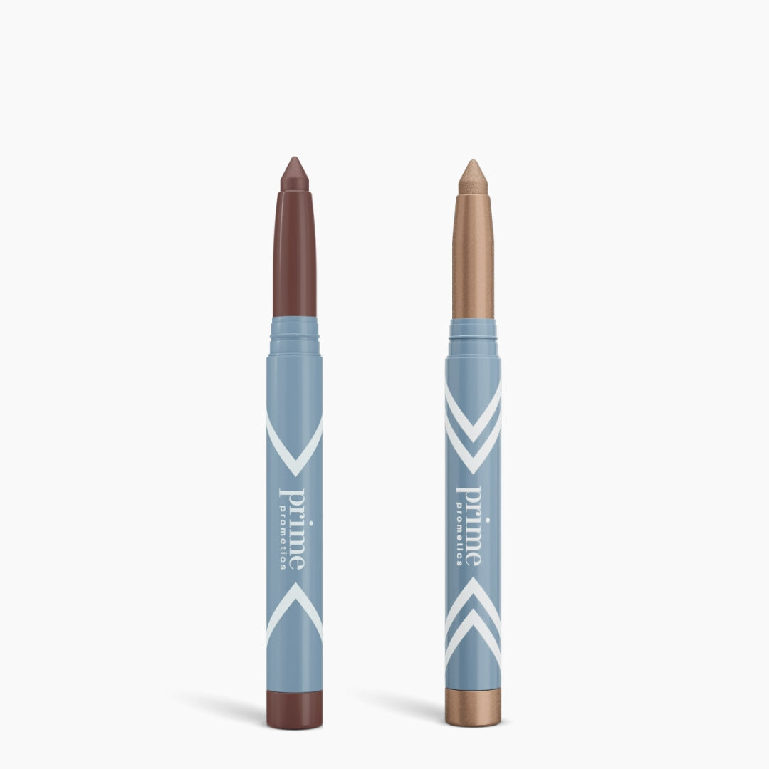 Two blue PrimePrometics™ Complete Eye Sticks stand upright on a white background: the left has a brown tip and base, the right has a light bronze tip. Both provide matte eyeshadow shades to brighten your eyes.