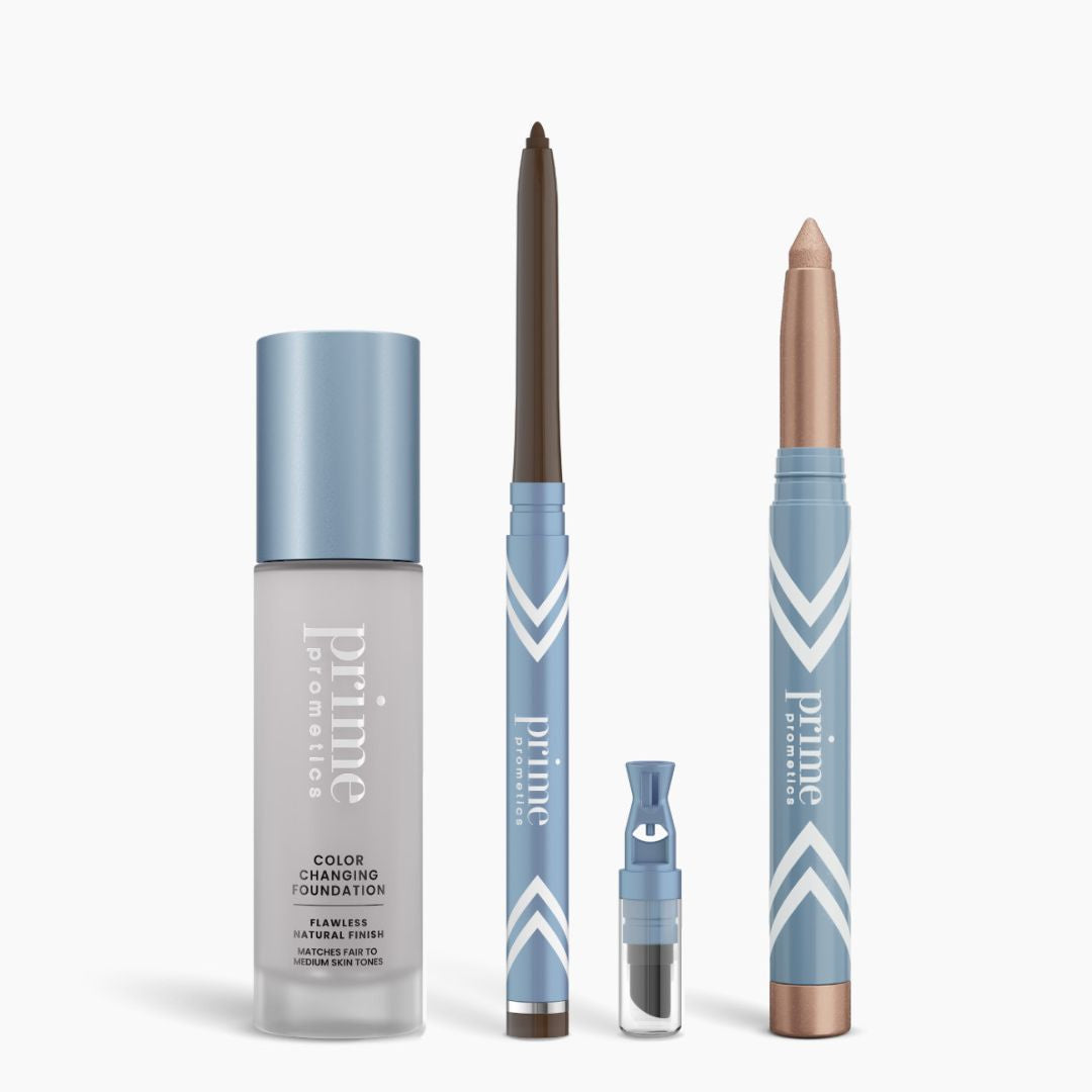 Four PrimePrometics™ All-Day Confidence Bundle products—color-changing foundation, brown glide eyeliner, makeup vial with applicator, and shimmery eyeshadow stick—stand upright on a white background.