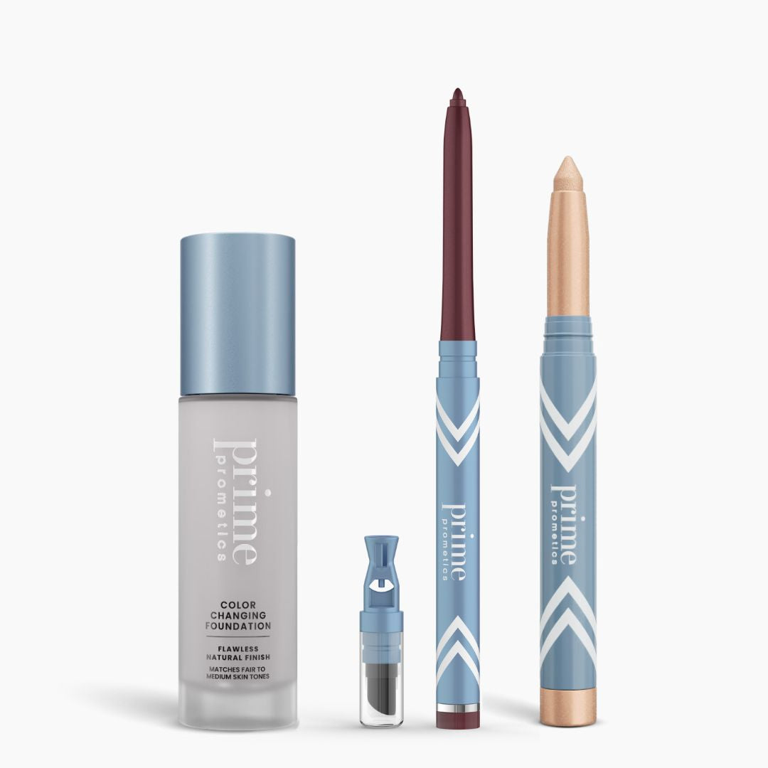 Four PrimePrometics™ All-Day Confidence Bundle products in blue packaging stand upright: a color changing foundation, a dropper vial, a burgundy pencil, and a gold cream stick. The background is white.