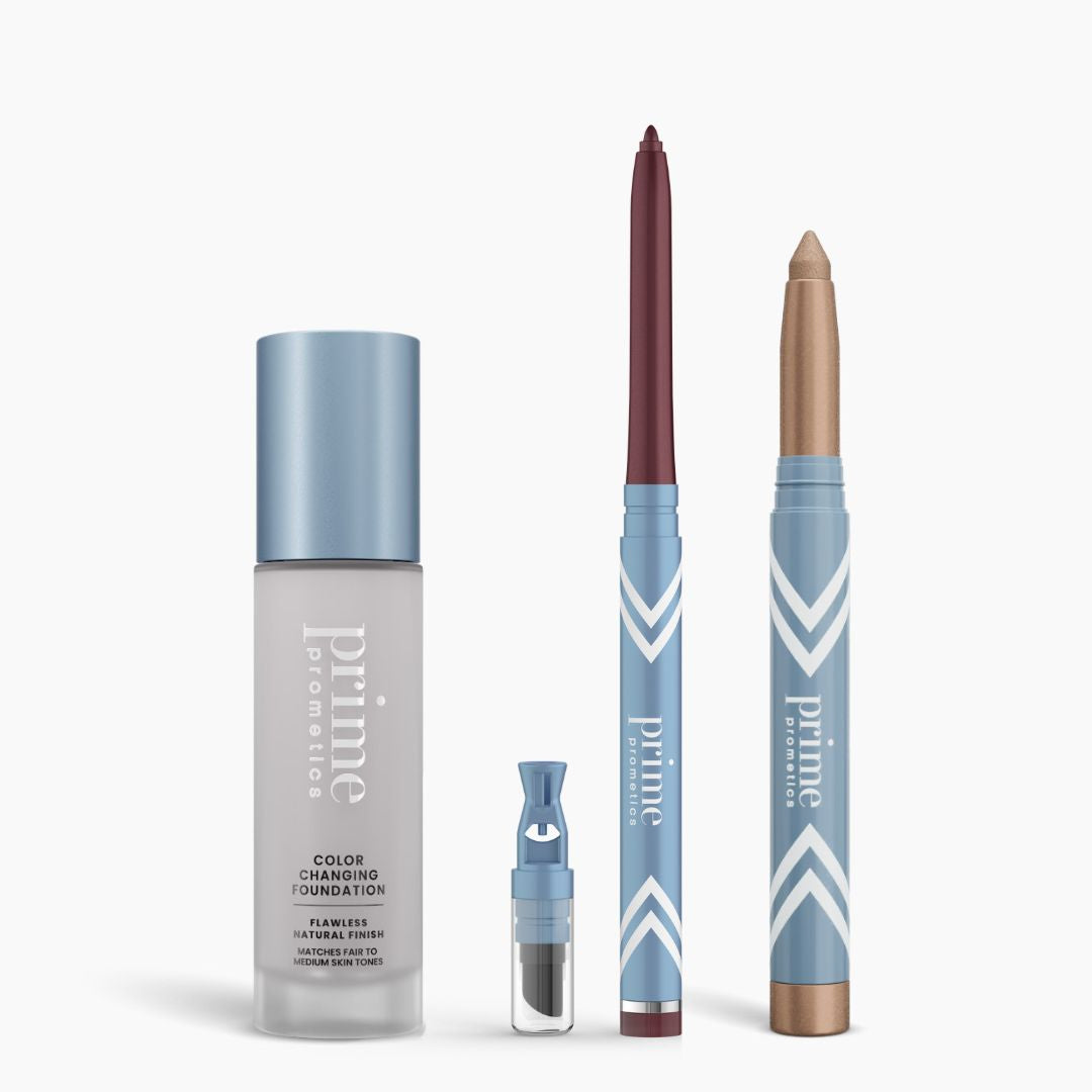 The All-Day Confidence Bundle by PrimePrometics™ features four products in blue and white packaging: a color changing foundation bottle, a brightener vial, a dark mauve twist-up pencil, and a golden eyeshadow stick.