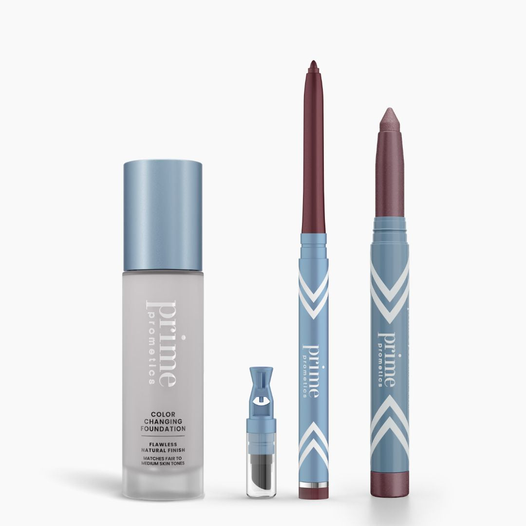 The PrimePrometics™ All-Day Confidence Bundle is shown upright: a color changing foundation, brightener vial, mauve pencil, and glide eyeliner stick—all in blue and silver packaging on a white background.