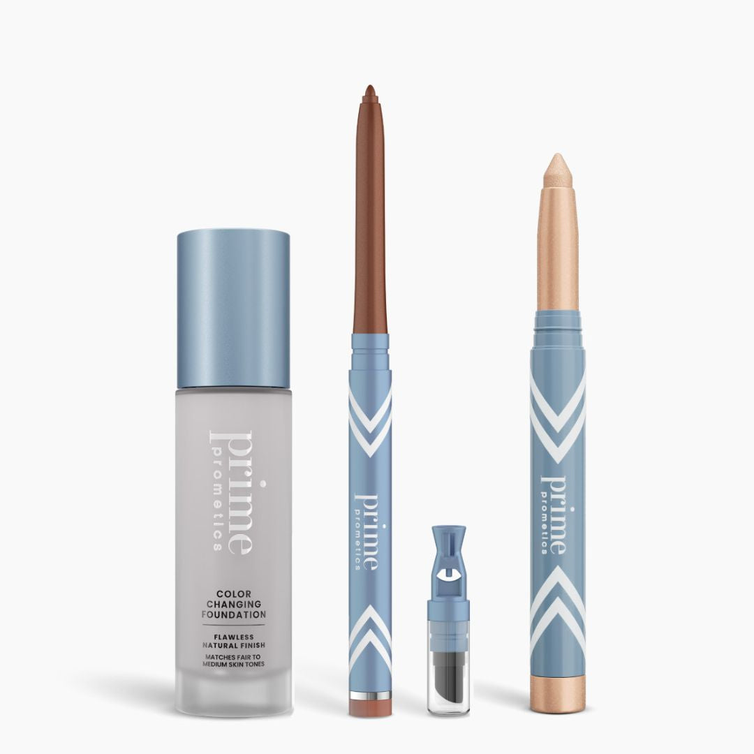 The PrimePrometics™ All-Day Confidence Bundle features four products—a color changing foundation, brown glide eyeliner pencil, brightener vial with brush, and beige eyeshadow stick—arranged on a white background in light blue packaging.
