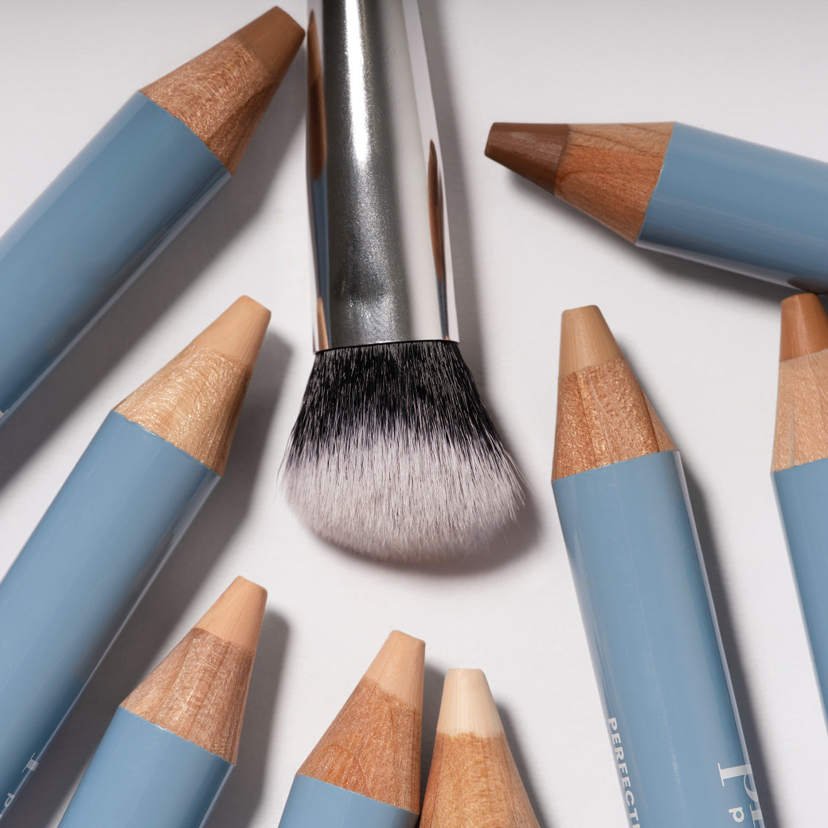 PrimeSkin Concealer Brush surrounded by Prime Prometics Perfecting Concealer Pencils in multiple shades
