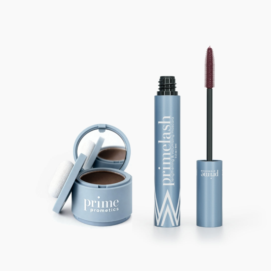 The Beauty Essentials set by PrimePrometics™ features an open blue hairline powder makeup with sponge and a blue tube of PrimeLash mascara, wand exposed, all displayed on a white background.