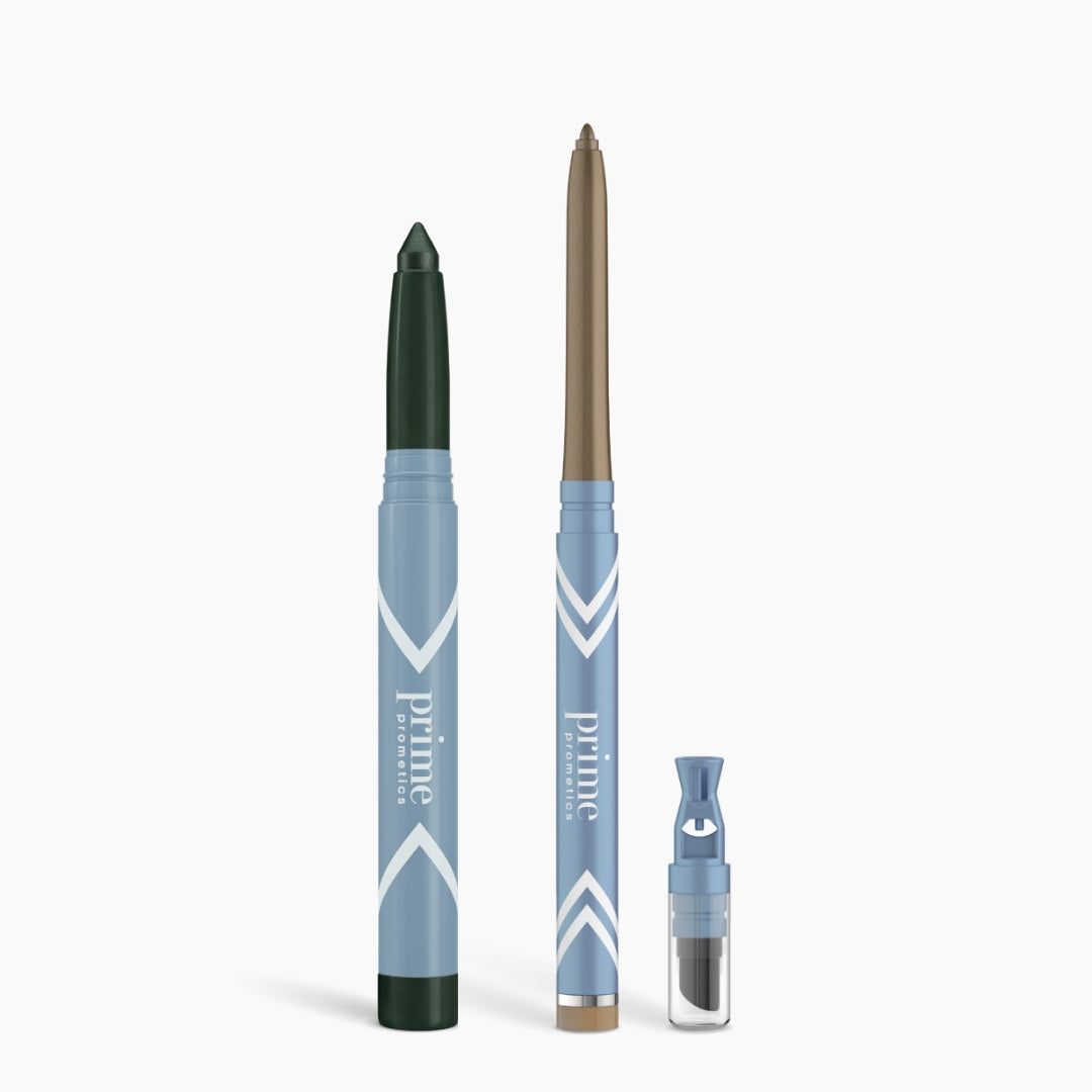 Three PrimePrometics™ Eye Lift Duo pencils in dark green, bronze, and black with varied tips stand upright with a small blue sharpener on a white background—ideal eyeliner for women over 50.