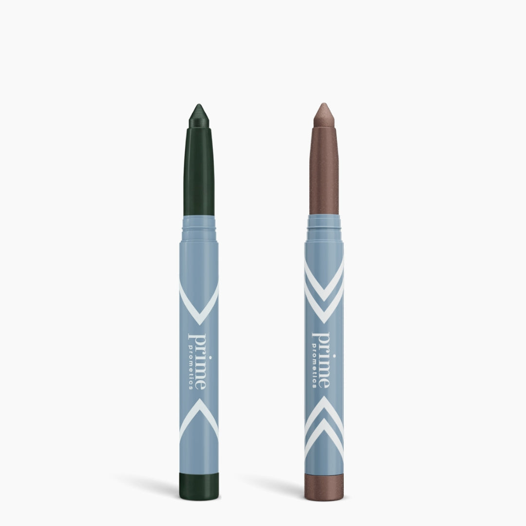 The Complete Eye Sticks Kit by PrimePrometics™ features two versatile eye crayons—dark green and shimmery brown—in light blue twist-up tubes labeled PrimePrometics™, shown upright on a white background.