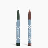 Two blue PrimePrometics™ Complete Eye Sticks Kit makeup sticks stand upright against a white background: the left is a matte dark forest green eyeshadow, and the right is a shimmery bronze, both with rounded tips.