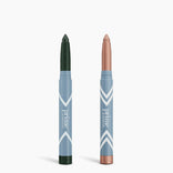 Two Complete Eye Sticks Kit makeup sticks from PrimePrometics™ stand upright in blue and white tubes: the left is dark green matte eyeshadow, the right is a rose gold shimmery eye brightener. Both are labeled "prime.