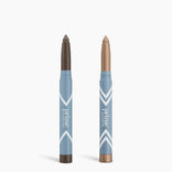 Two blue and white PrimePrometics™ Complete Eye Sticks Kit products stand upright—a dark brown matte eyeshadow stick on the left and a shimmery beige eye brightener stick on the right—both labeled “prime” on a white background.