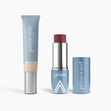 Three blue PrimePrometics™ Complete Face Bundle products on a white background: a tube of CC+ Cream, an open Pigment lipstick showing a dark red shade, and the matching cap beside it.