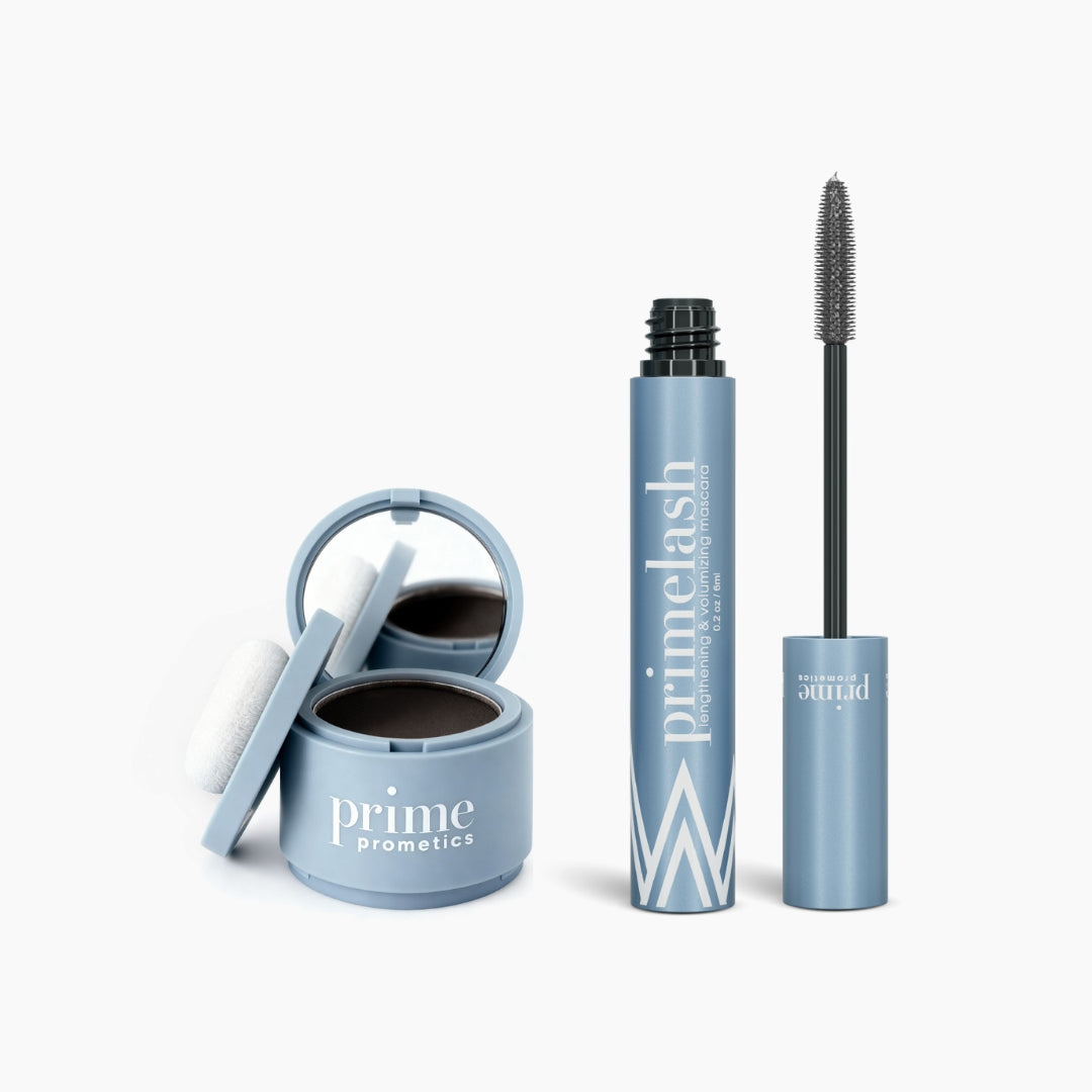 The PrimePrometics™ Beauty Essentials set, featuring a blue compact with mirror and applicator sponge and an open PrimeLash mascara, is displayed on a white background.