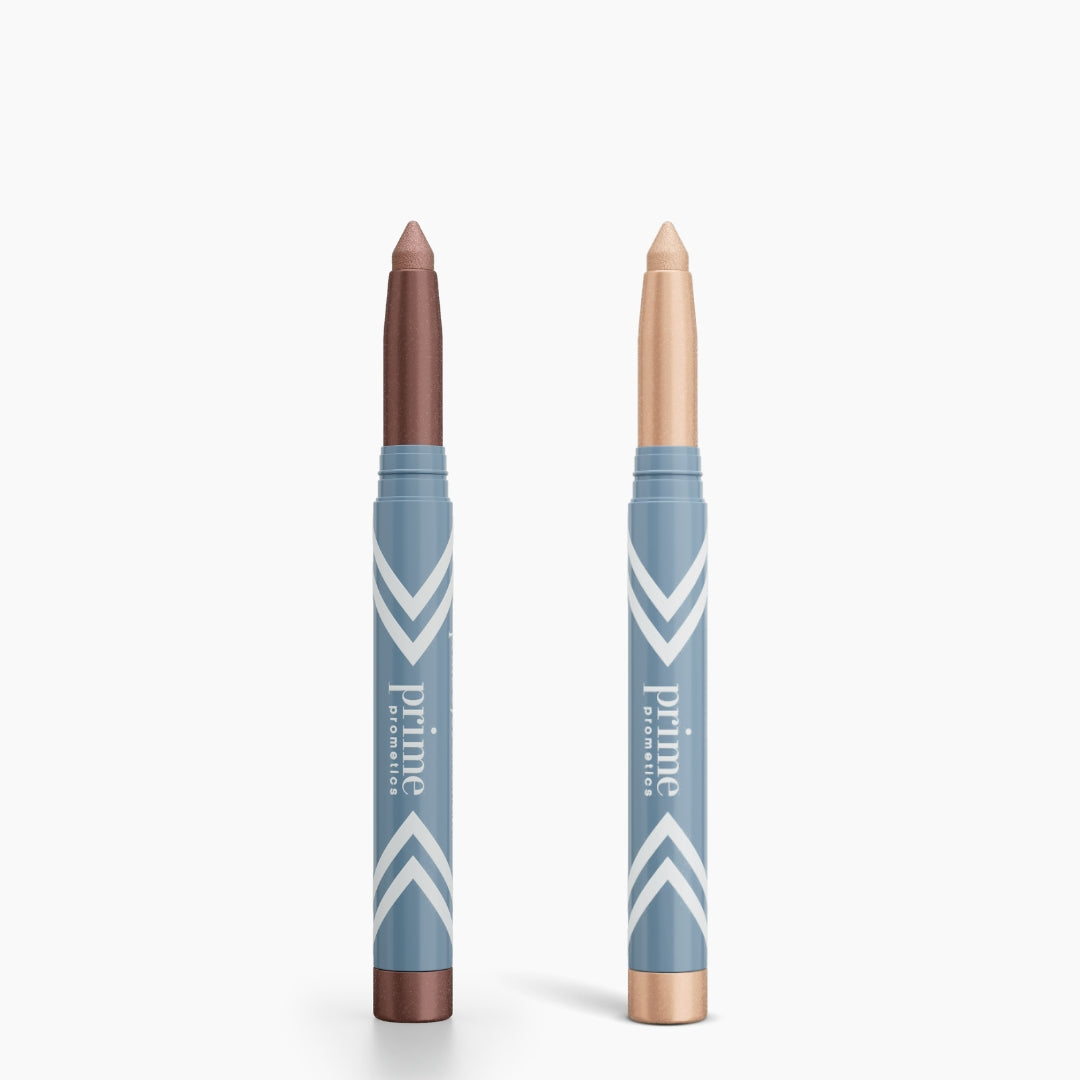 Two PrimePrometics™ PrimeEyes Eye Brightener sticks are shown with caps off—one shimmery brown, one shimmery light beige—both in blue chevron packaging. Perfect duo for effortless eye brightening and care.