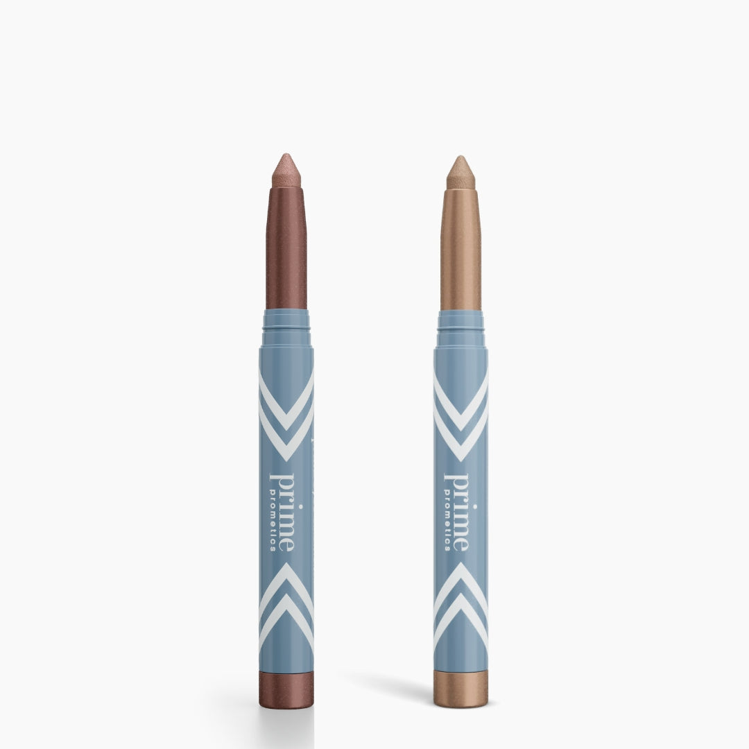 Two blue PrimePrometics™ PrimeEyes Eye Brightener sticks with white stripes stand upright—one with a shimmery brown tip, the other gold—ideal as eye brighteners or under eye cream, shown on a white background.