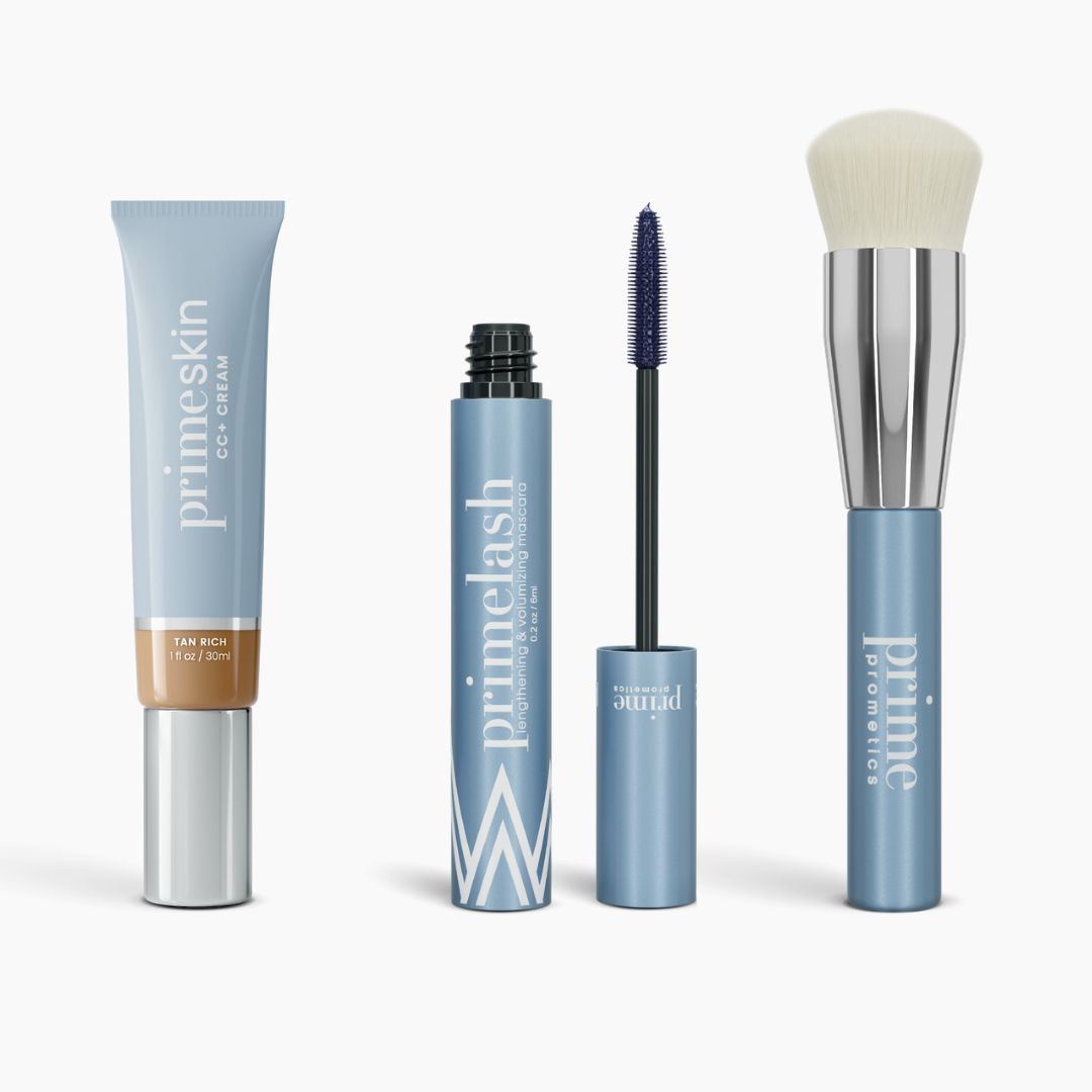 The PrimePrometics™ Effortless Beauty Complete Bundle features a CC+ Cream tube, an open primelash Mascara with wand, and two Foundation Brushes in light blue, all standing upright against a white background.