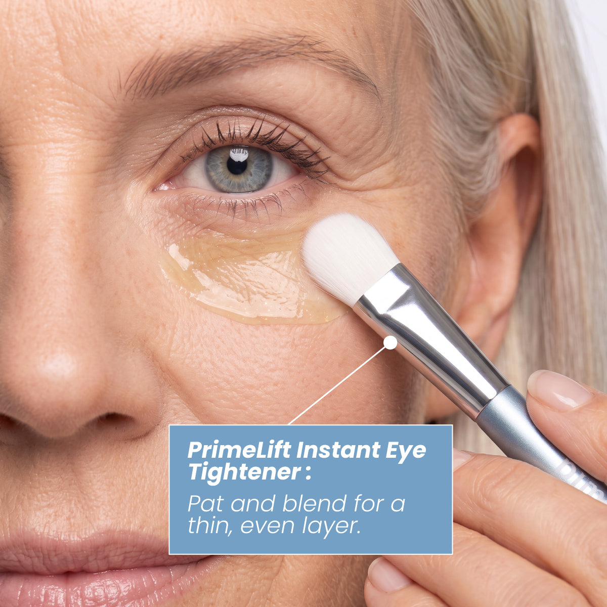 A person uses a PrimeLift Precision Applicator Brush to pat and blend a thin, even layer of eye tightener under their eye.