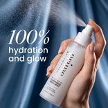 Eine Hand hält ein Prep-Set-Refresh Luminous Skin Mist in der Hand, aus dem ein feiner, strahlender Nebel versprüht wird, während im Hintergrund der Schriftzug 100 % Feuchtigkeit und Strahlkraft zu lesen ist.