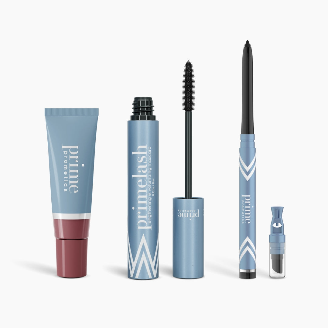 The Compliments Bundle by PrimePrometics™ is displayed in a row: a tube, an open PrimeLash Mascara with wand, a PrimeEyes Glide Eyeliner pencil, and a small vial with applicator—all against a white background.