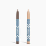 Two blue PrimePrometics™ Complete Eye Sticks Kit are upright on a white background; one has a taupe Matte Eyeshadow tip, the other a shimmery champagne Eye Brightener tip.