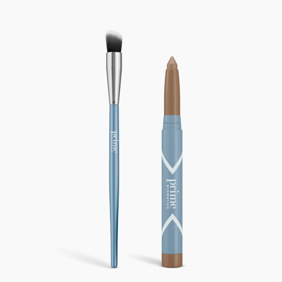A blue Cream Eyeshadow Brush with a silver ferrule and black-and-white bristles stands next to a blue twist-up stick with a matte brown eyeshadow tip. Both are labeled Seamless Shadow Bundle Matte by PrimePrometics™.