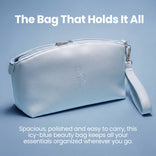 A sleek, icy-blue PrimePrometics™ beauty bag with a convenient wrist strap rests on a light blue background. Above, white text proclaims: Prime Mini Essentials Travel Kit—The Bag That Holds It All. Below, descriptive text emphasizes the bag’s spacious, polished, and easy-to-carry design—ideal for organizing your travel makeup kit and beauty essentials like mini foundation and more.