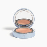 A sleek silver compact with mirror reveals a beige pressed powder foundation. The front features RP initials and pairs perfectly with PrimePrometics™ Undereye Brightening Corrector to visibly diminish dark circles.