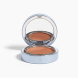 The PrimePrometics™ Undereye Brightening Corrector comes in a sleek, light blue circular case with a mirror and features a warm-toned, color-correcting balm to effectively conceal dark circles.
