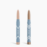 Two blue Complete Eye Sticks Kit tubes by PrimePrometics™ stand upright on a white background; each has a twist-up cream tip—light beige on the left for brightening, metallic bronze on the right for matte eyeshadow.